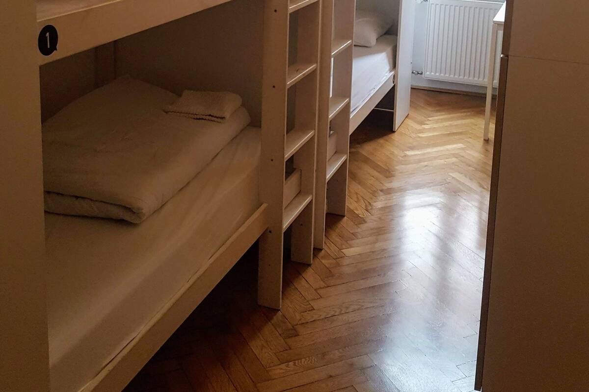 Ein Schlafsaalzimmer mit Etagenbetten, einem Heizkörper und einem Fenster mit Vorhängen.