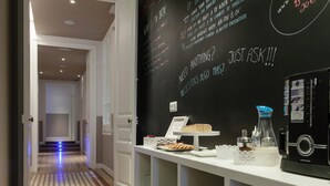 A hallway with a patterned floor, a blackboard with text, a coffee machine, and a display of food items. - Ecozentric (Barcelona)