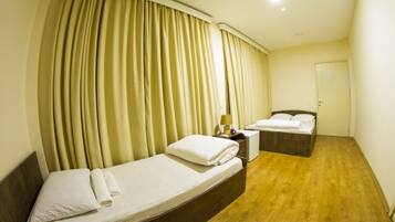 A hotel room with a single bed, a nightstand, a lamp, and a wooden floor.