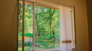 Ein Zimmer mit einem großen Fenster und Blick auf ein bewaldetes Gebiet.
