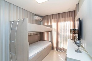 Ein kompaktes Hotelzimmer mit Etagenbett, einer Leiter, einem Flachbildfernseher und einem Globus auf einem kleinen Tisch.