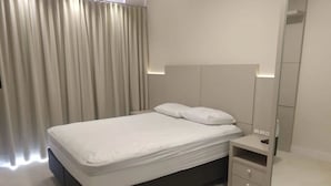 Een moderne slaapkamer met een bed, nachtkastje en spiegel.