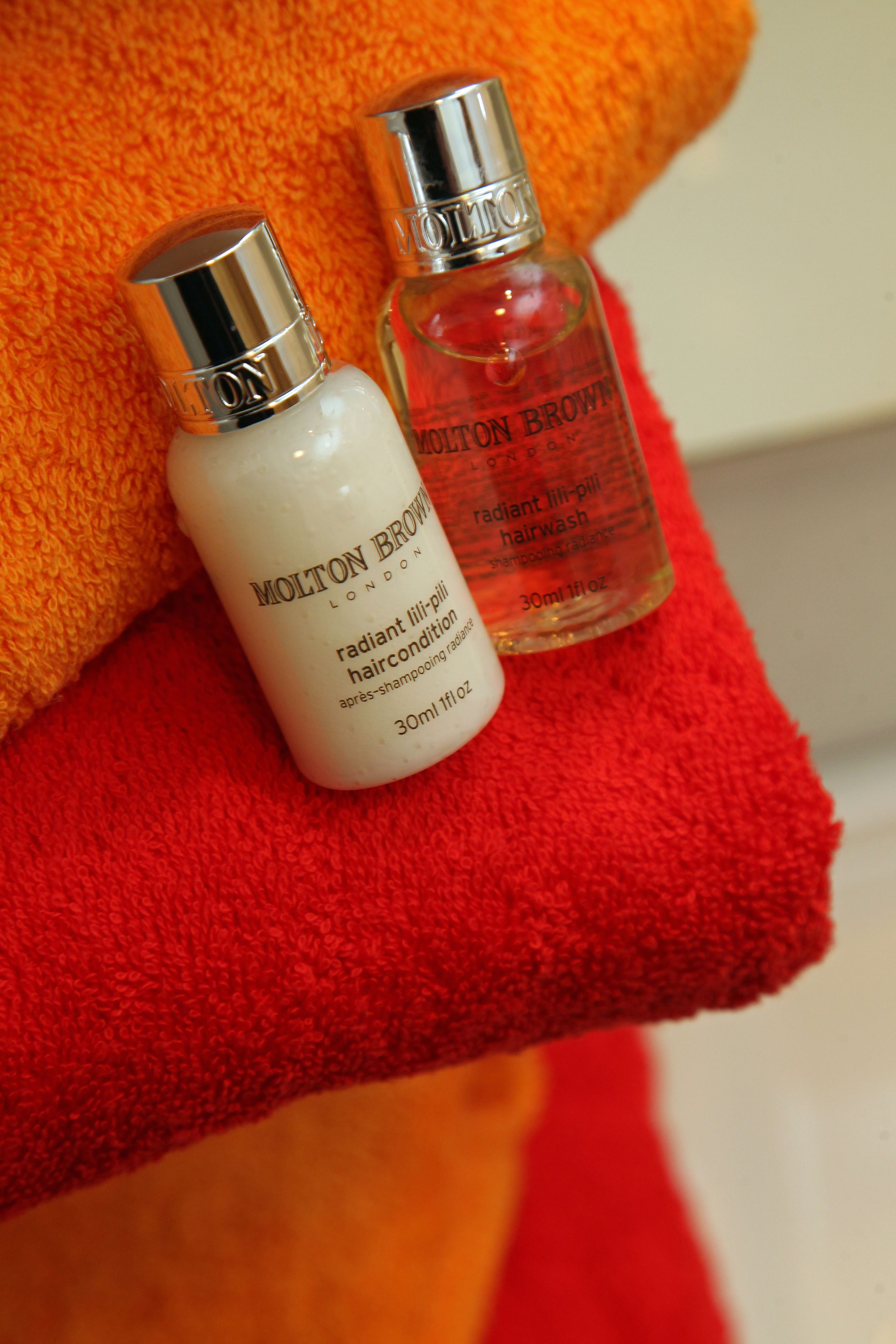 Two bottles of Molton Brown haircare products on a red towel.