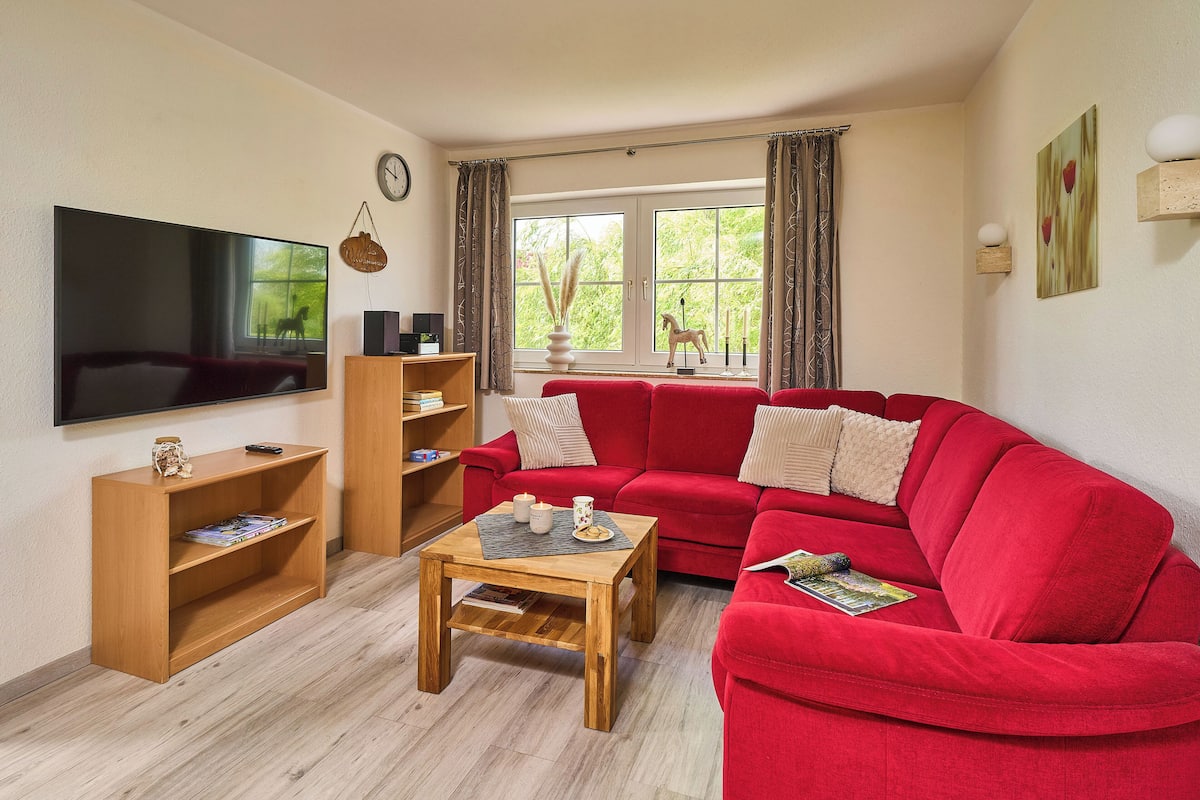 A living room with a red sofa, wooden coffee table, and a flat-screen TV.