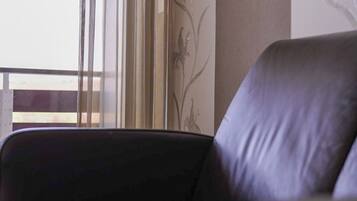 A leather chair in a room with a window, a wall with floral wallpaper, and a wooden railing.