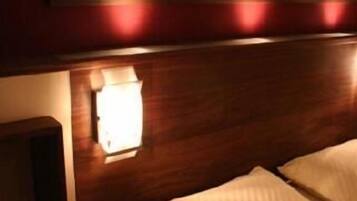 Ein Hotelzimmer mit Holz-Kopfteil, einer Nachttischlampe und einem Bett mit weißer Bettwäsche.
