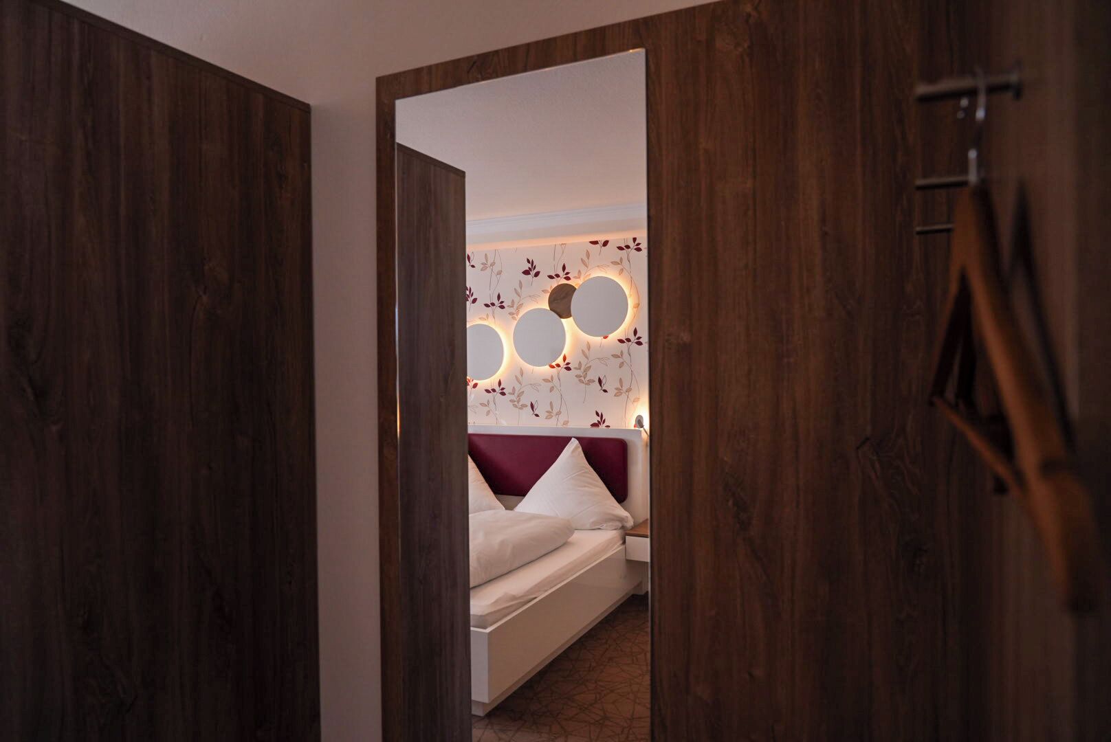 A bedroom with a bed, a headboard with circular light fixtures, and a wooden door.