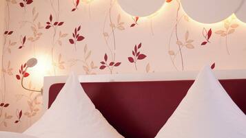 A hotel room with a bed, a red headboard, and wall-mounted circular light fixtures.