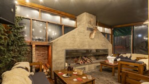 Un ambiente cálido y acogedor con chimenea de piedra, muebles de madera y un árbol de Navidad.