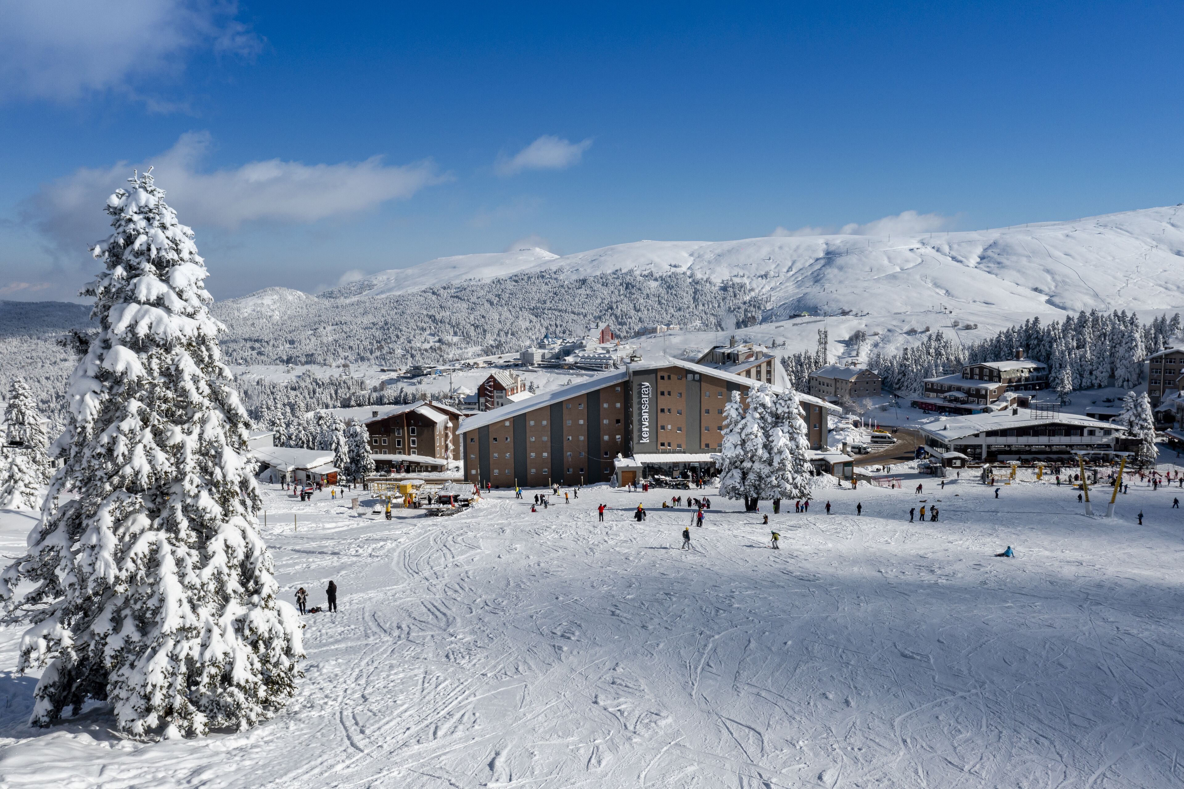 A snow-covered ski resort with a large lodge, ski slopes, and a mountain backdrop.
