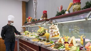 Un bufé con diversas opciones de comida y un cocinero preparando alimentos.