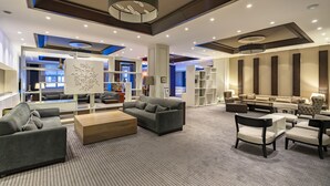 Un espacioso vestíbulo de hotel con muebles modernos, una zona de estar central y una gran decoración mural.