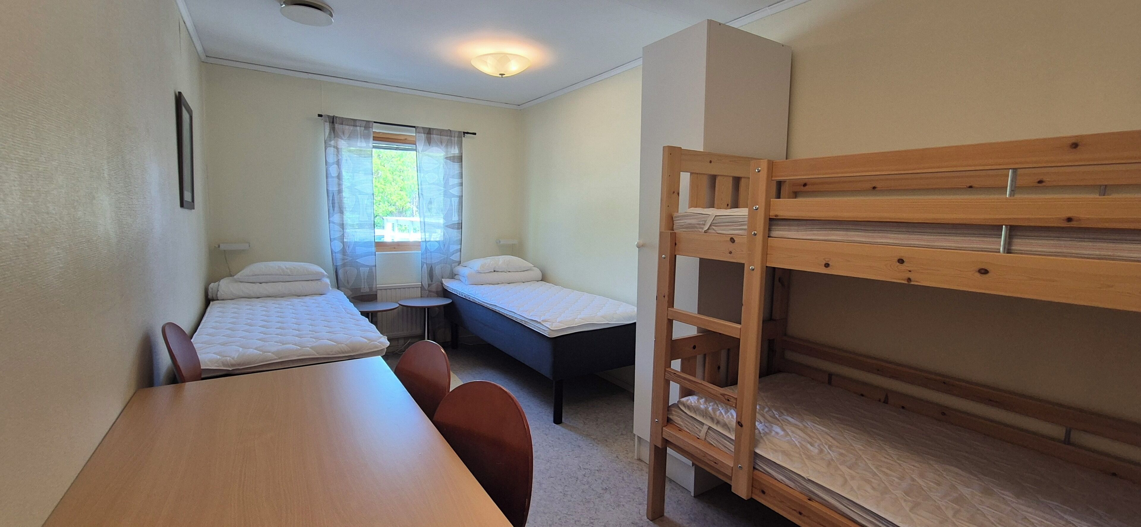 Una habitació amb lliteres, una taula petita i dues cadires.