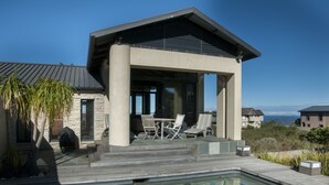 A modern house with a pool, outdoor seating, and a view of the ocean. - 10 Martingale (Knysna)