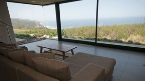 Un salon moderne doté d’une grande fenêtre donnant sur un paysage côtier.
