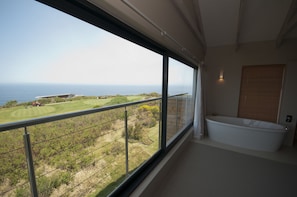 Un balcón con vista al océano y a un campo de golf.