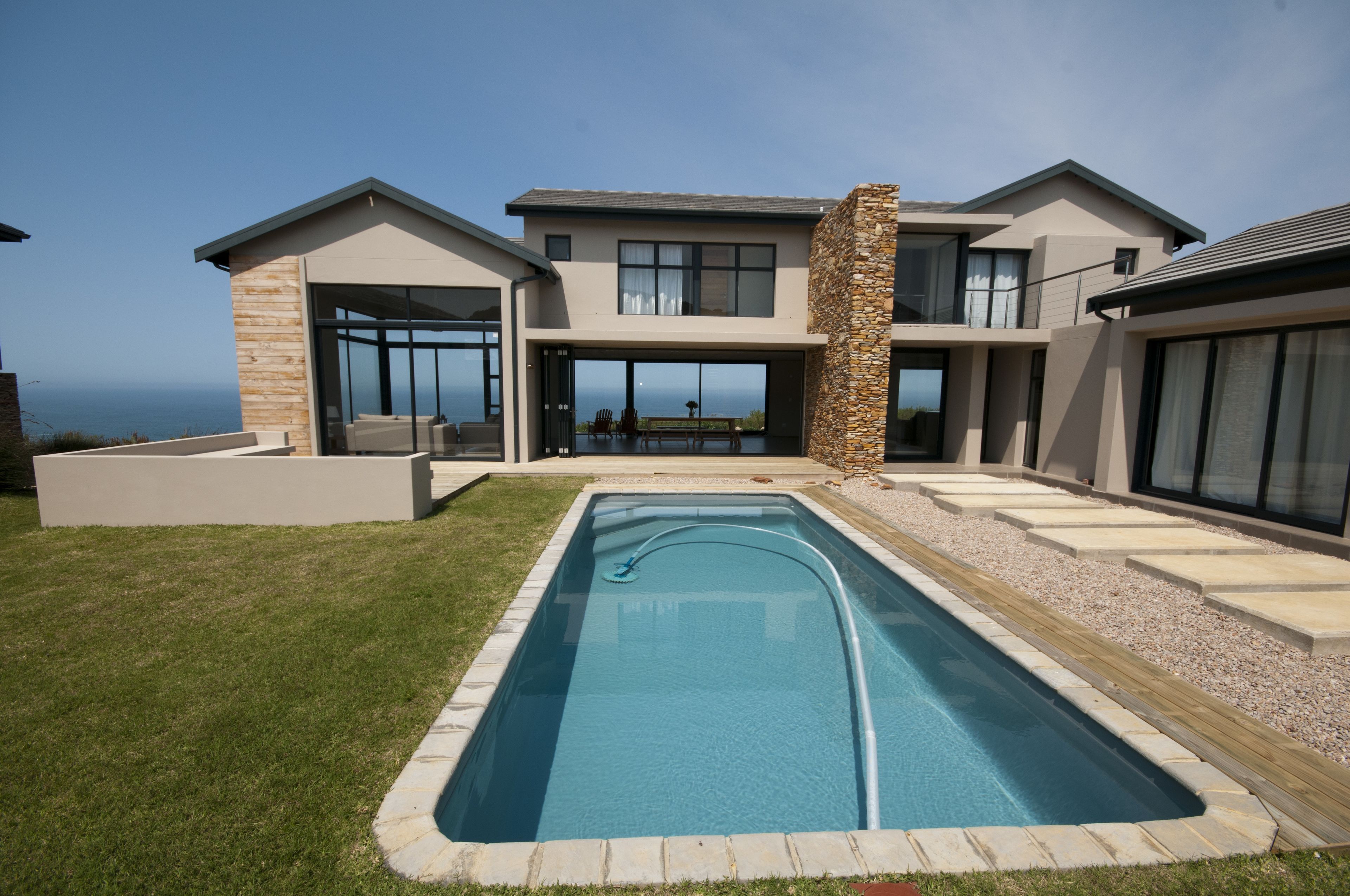 Una casa moderna con piscina, ventanas amplias y vista al océano.