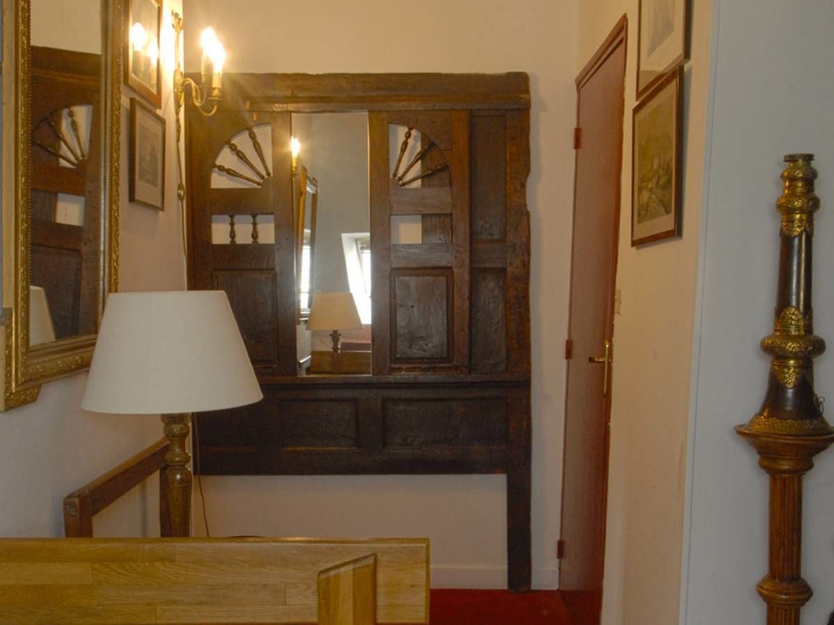 Et værelse med dør i træ, et spejl, en lampe og en seng.