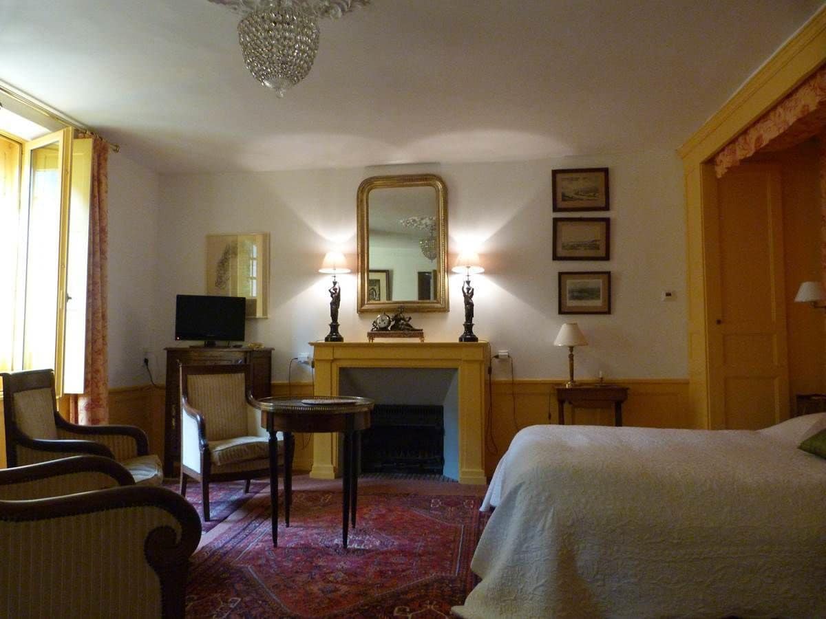 Ein Hotelzimmer mit einem Bett, einem Fernseher, einem Kamin, einem Spiegel und zwei Sesseln.