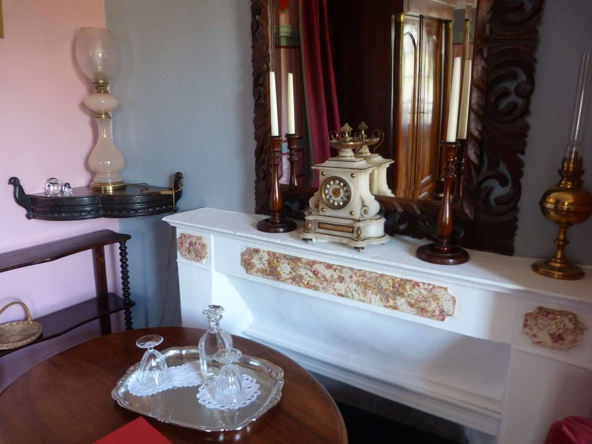 A room with a wooden table, a white fireplace mantel with a clock, and a mirror.
