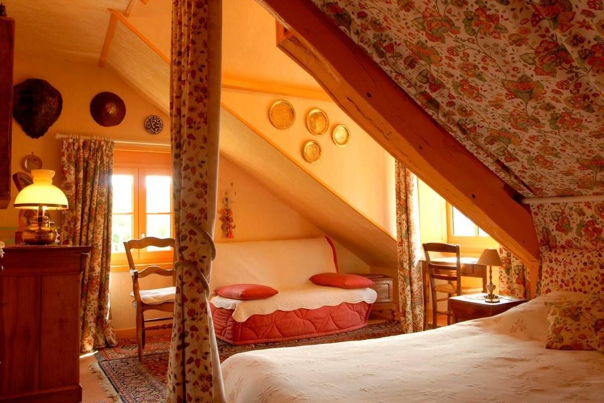 A cozy attic bedroom with a bed, a desk, and a chair.