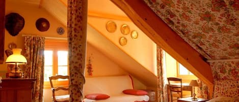 A cozy attic bedroom with a bed, a desk, and a chair.