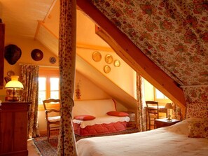 A cozy attic bedroom with a bed, a desk, and a chair.