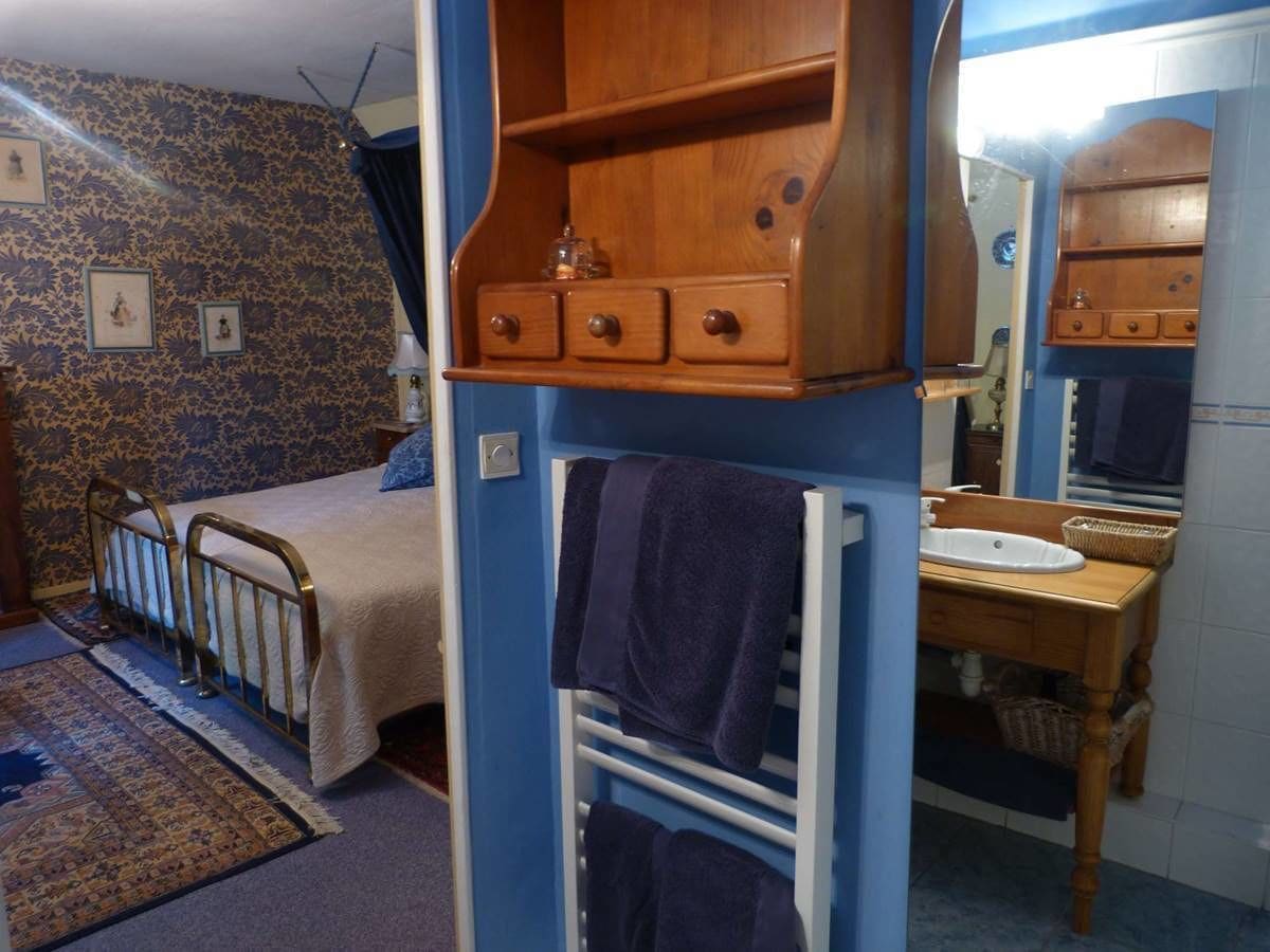 Une chambre à coucher comprenant un lit, une commode, un miroir et une salle de bain avec un lavabo et un porte-serviettes.