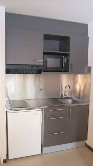 A compact kitchen with a microwave, stove, sink, and a small refrigerator. - Résidence Cévéo du Pleynet (Le Haut-Bréda)