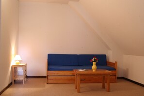 A small room with a blue sofa, a wooden table, a lamp, and a vase with flowers.