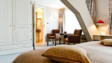 A hotel room with a bed, two armchairs, a table, and a wardrobe.