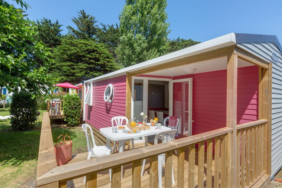 A mobile home with a covered patio area, a dining table, and a small garden.