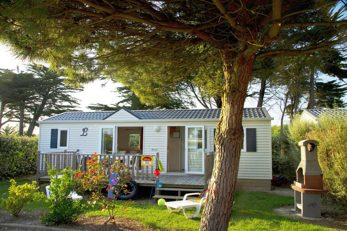 A mobile home with a porch, a small garden, and a bird feeder.