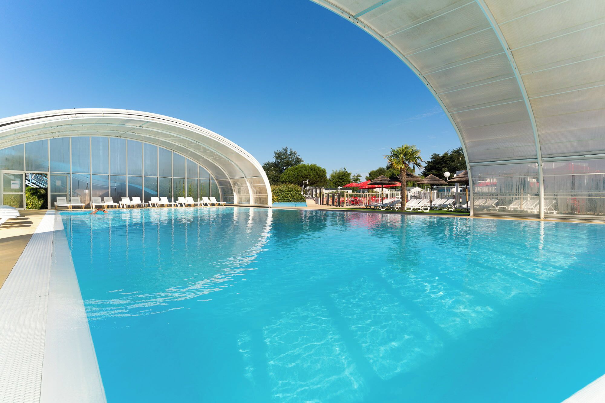 Een binnenzwembad, een buitenzwembad en parasols bij het zwembad