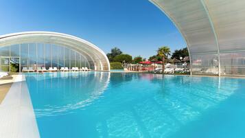 Een binnenzwembad, een buitenzwembad en parasols bij het zwembad