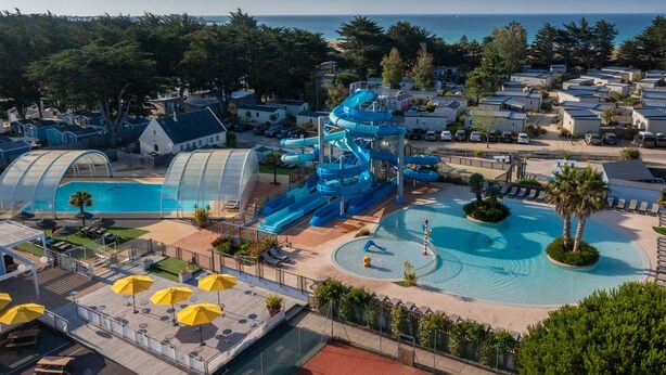 A water park with multiple slides and pools, surrounded by villas and a beach. - Yelloh Village La Plage (Penmarch)