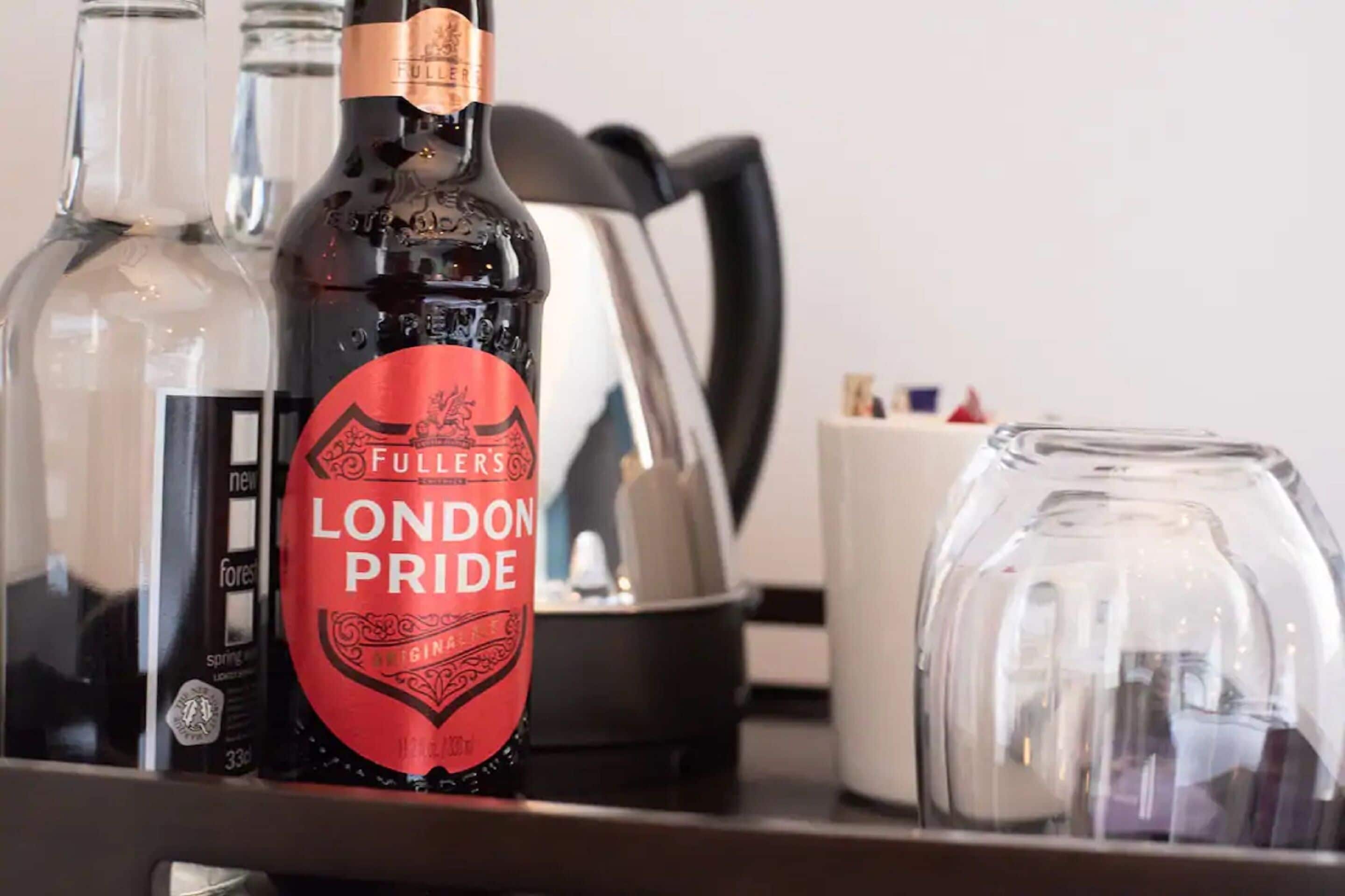 A bottle of London Pride gin, a glass, and a coffee maker on a table.