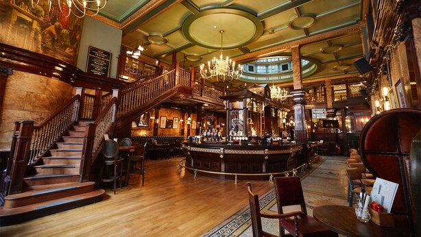A grand lobby with a central bar, a staircase, and a chandelier.