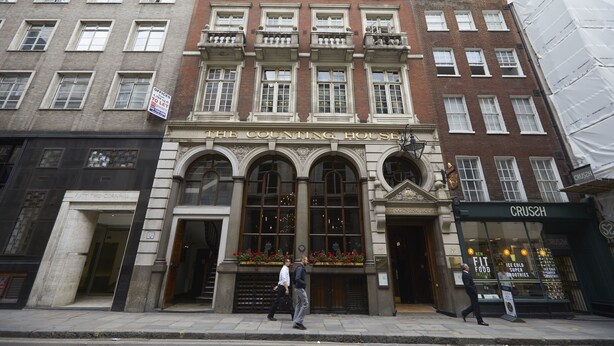 A historic building with a prominent entrance, large windows, and a sign indicating it is a counting house.
