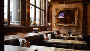 A restaurant interior with wooden tables, a large mirror, and a television on the wall.
