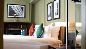 A hotel room with a bed, pillows, a nightstand, a lamp, and framed pictures on the wall.