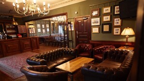 A bar area with leather seating, a wooden table, and a chandelier.