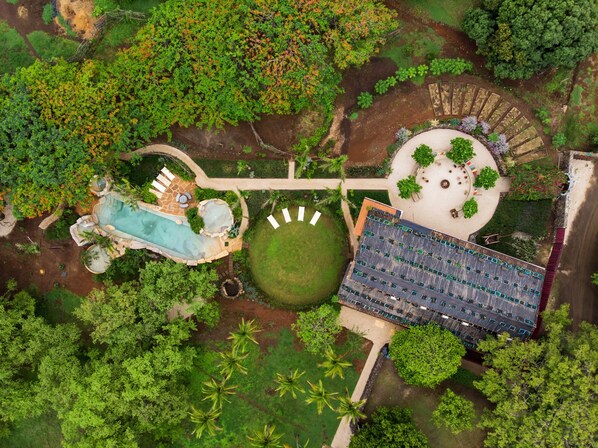 An aerial view of a resort with a swimming pool, a circular garden, and a building with a sloped roof. - Latica Lodge (Veintisiete de Abril)