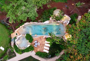An aerial view of a landscaped backyard with a swimming pool, stone patio, and surrounding greenery. - Latica Lodge (Veintisiete de Abril)