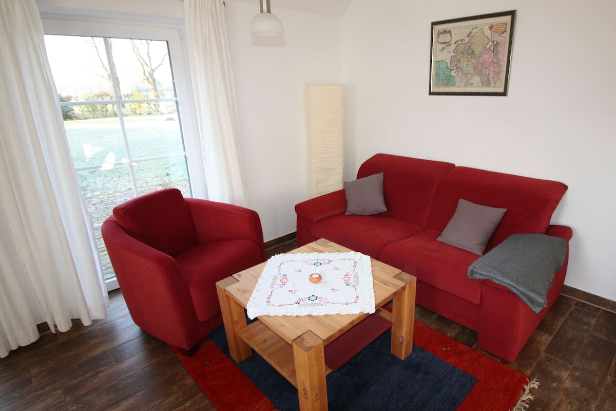 Ein Wohnzimmer mit einem roten Sofa, einem Holztisch und einer Karte an der Wand.