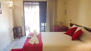 Una habitación de hotel con cama, una mesita, una silla y una ventana con cortinas.