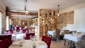 Een restaurant met gedekte tafels, houten balken in het plafond en stenen muren.
