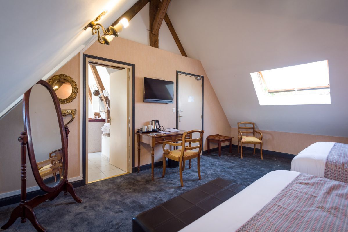 Une chambre à coucher comprenant un lit, un bureau, une chaise, un miroir et un téléviseur.