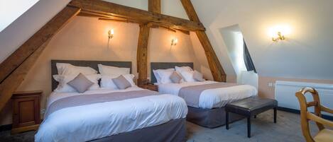 A bedroom with two beds, wooden beams, and wall sconces.
