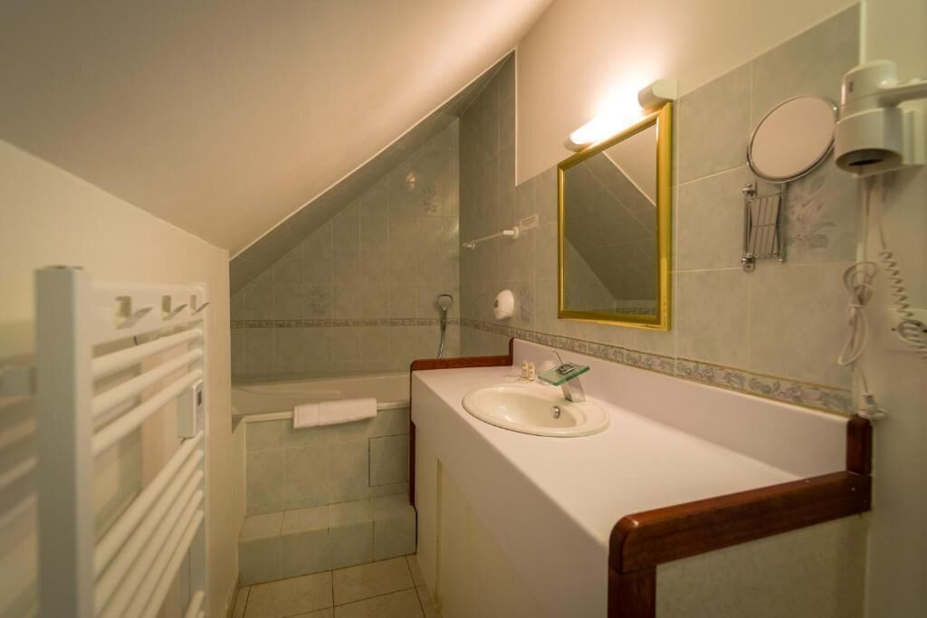 Un bagno con una vasca, un lavandino, uno specchio e un portascopevoli.